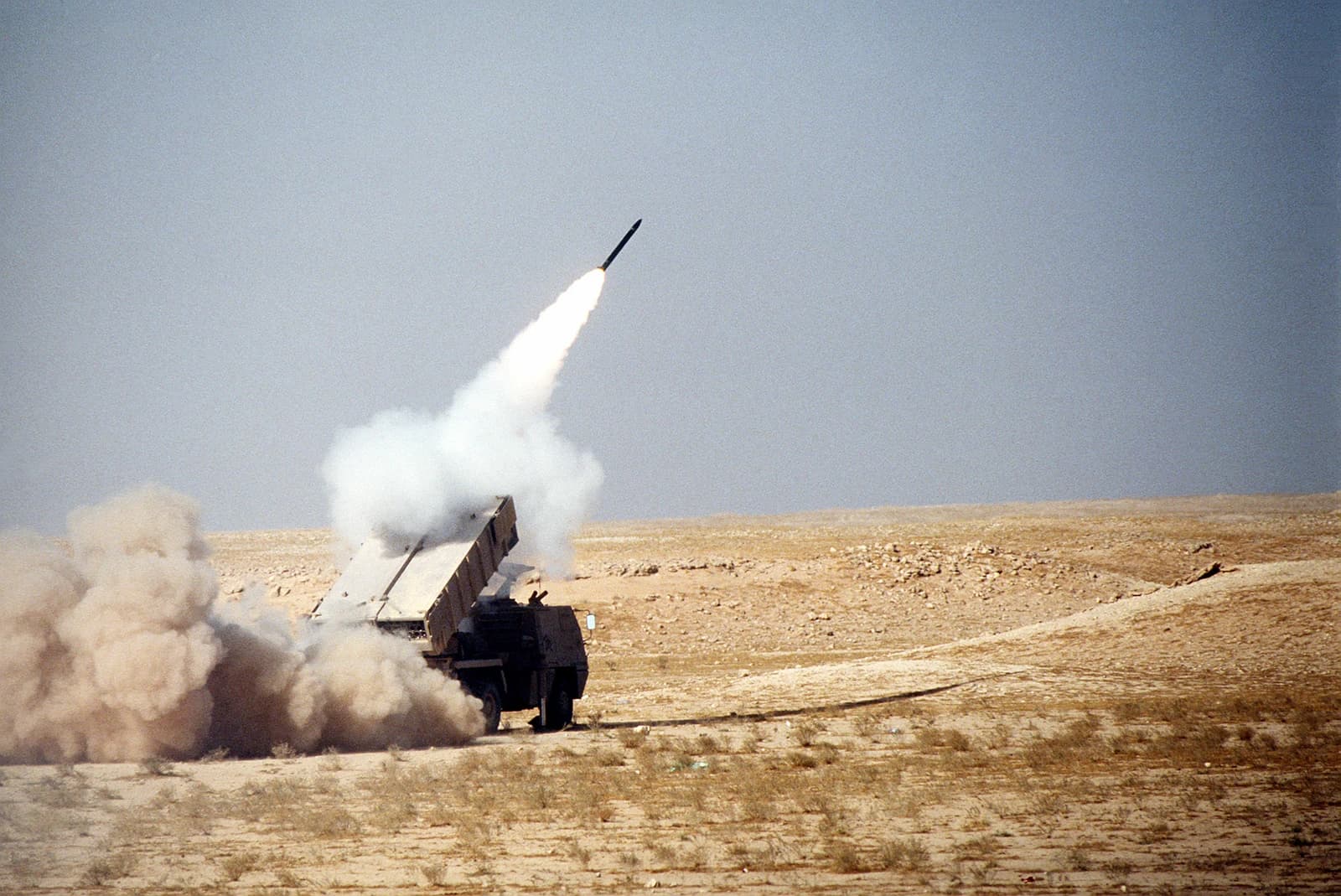 Military vehicle launching a rocket from a desert environment.