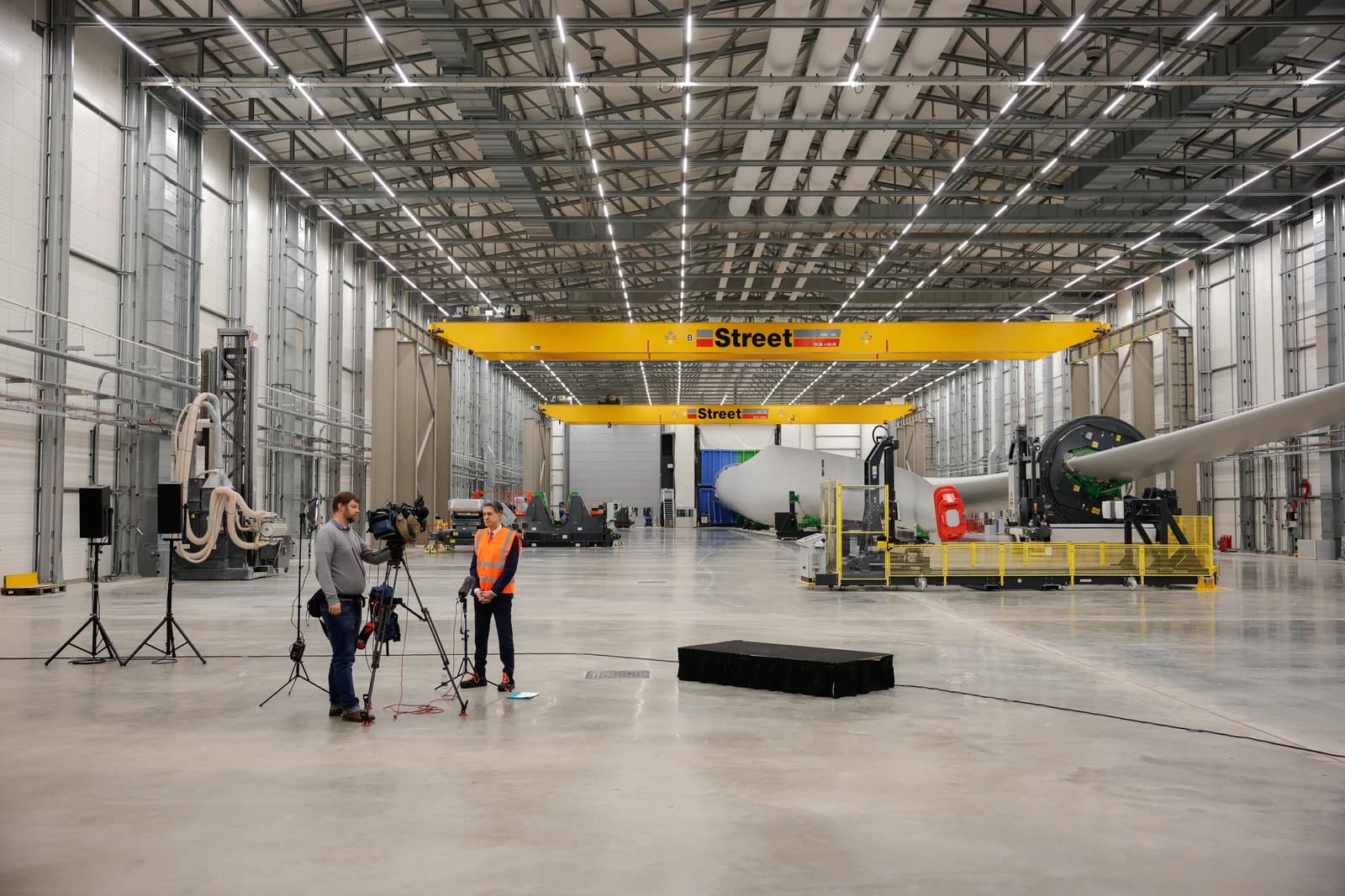 Ed Miliband, Energy Secretary, stands before a camera crew at a Siemens Gamesa facility.