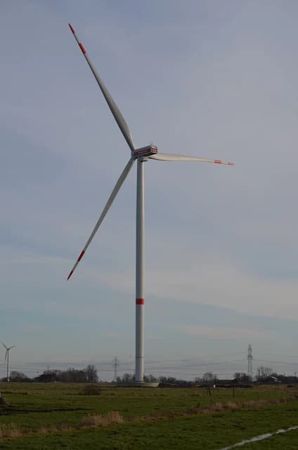 A Siemens Gamesa wind turbine with three blades stands in a green field.