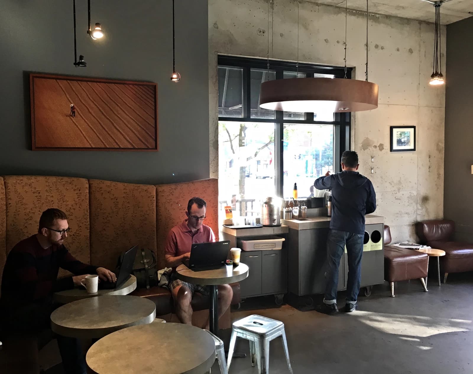 People inside Bridgehead Coffee Shop, one person at a counter, two people on laptops.