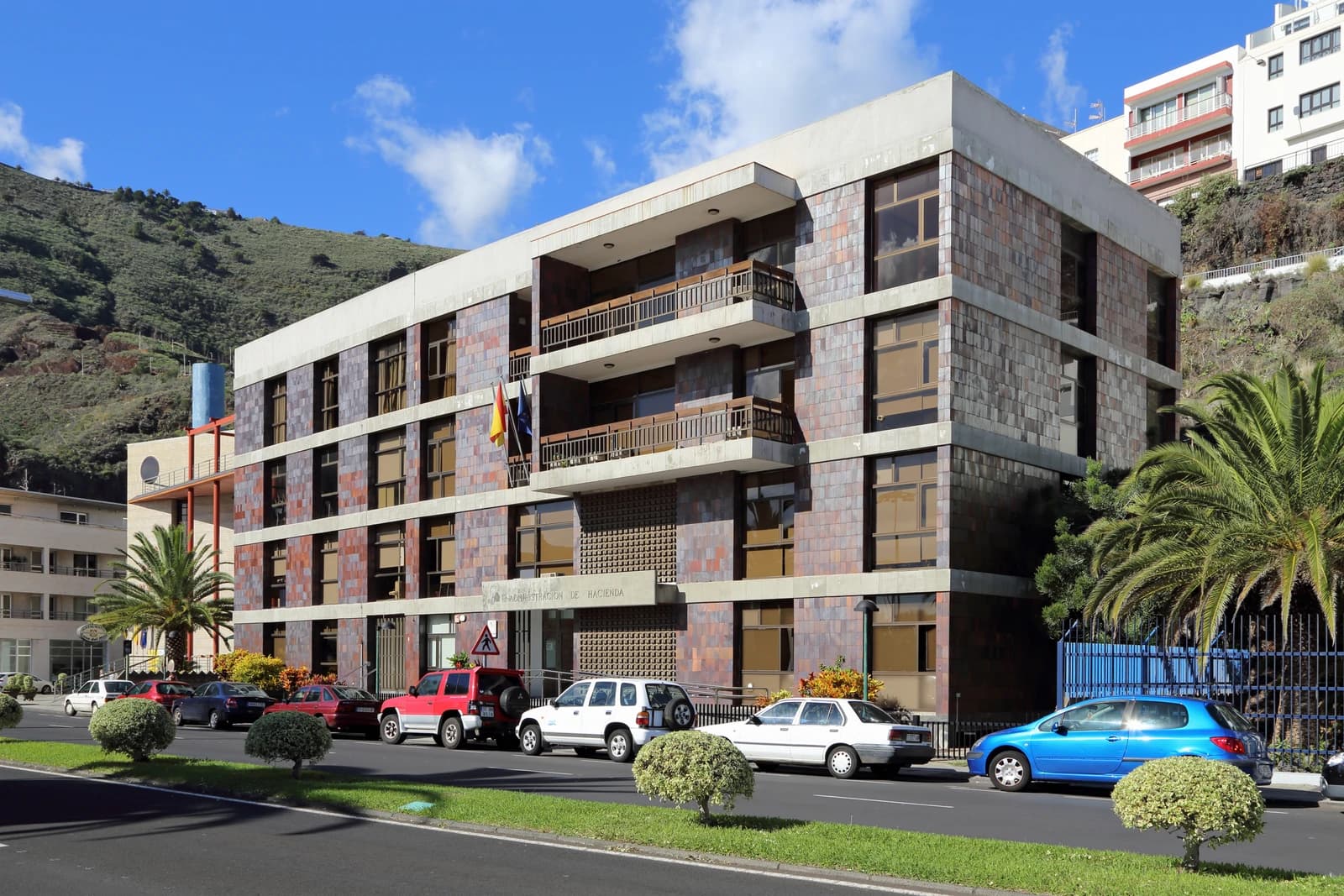 Exterior view of the Administracion de Hacienda building with cars parked on a street.