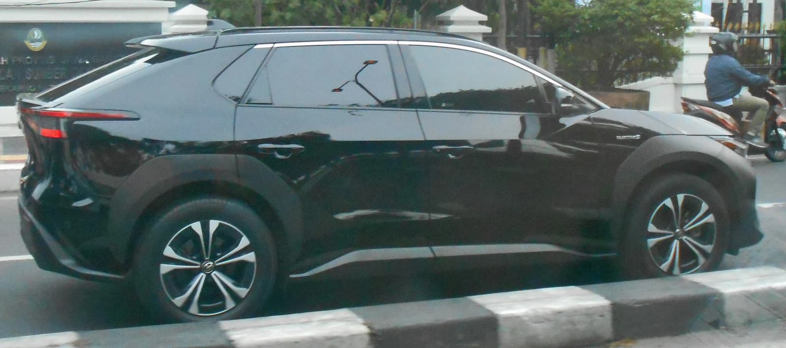 Dark-colored Toyota bZ4X electric vehicle on a city street, side view.