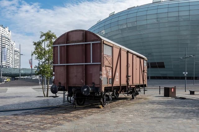 An old brown freight wagon on tracks in Bremerhaven, with a modern glass building behind it.