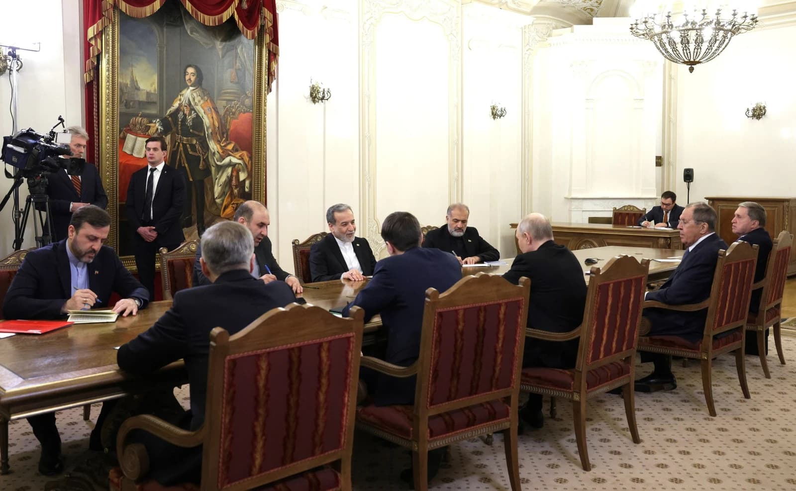 Iranian Foreign Minister Abbas Araghchi sits at a large conference table with other officials.