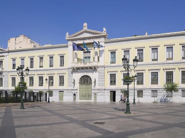 Exterior of the National Bank of Greece building with Greek and European Union flags.
