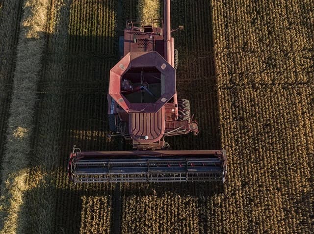 An aerial view of a combine harvester operating in a field.