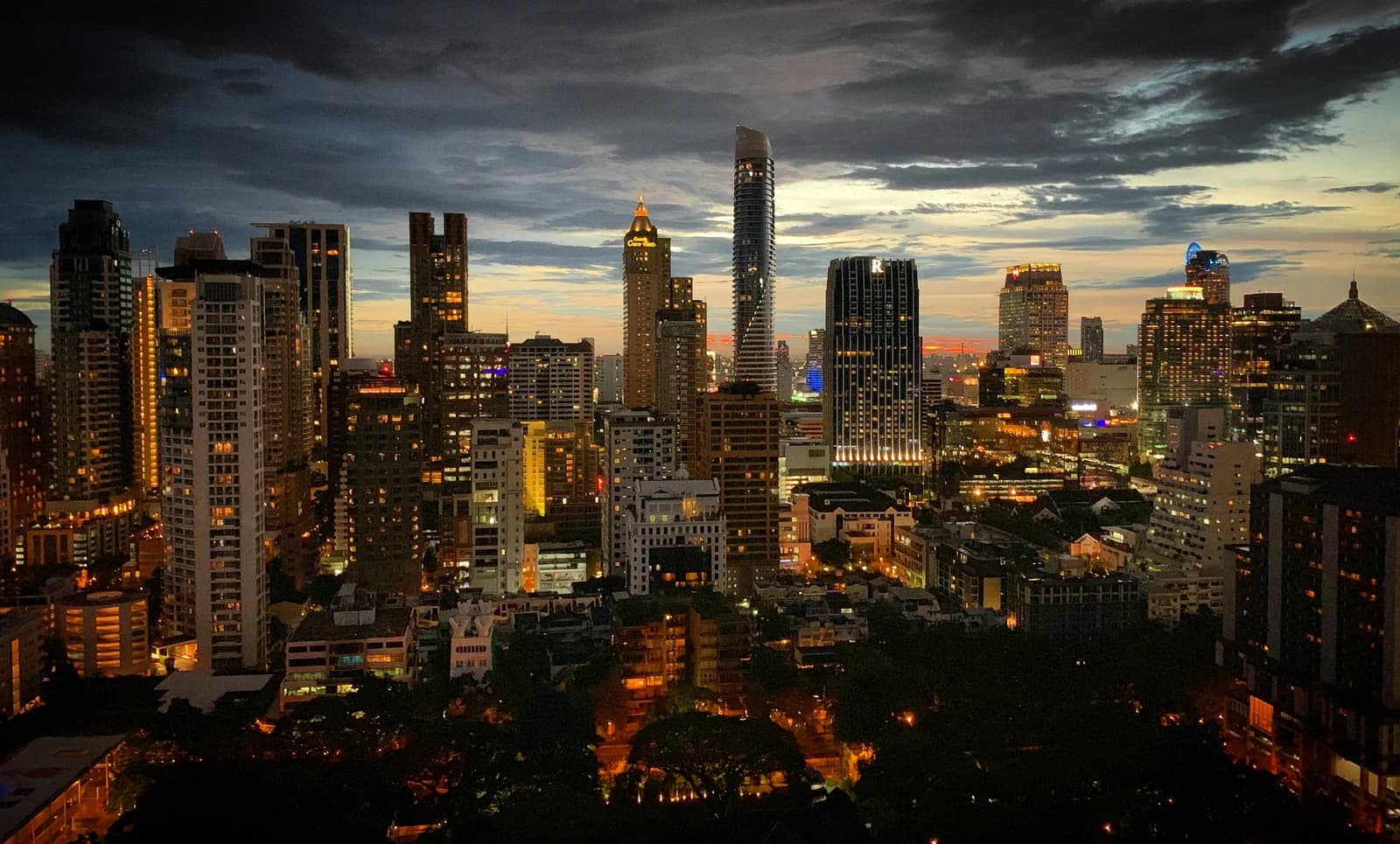 Modern skyscrapers and buildings illuminated at twilight in Ratchadamri district, Bangkok, Thailand.