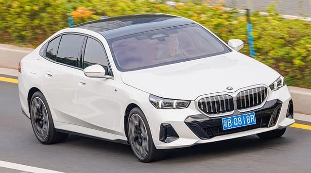 White BMW 5 Series LWB sedan driving on a road in China.