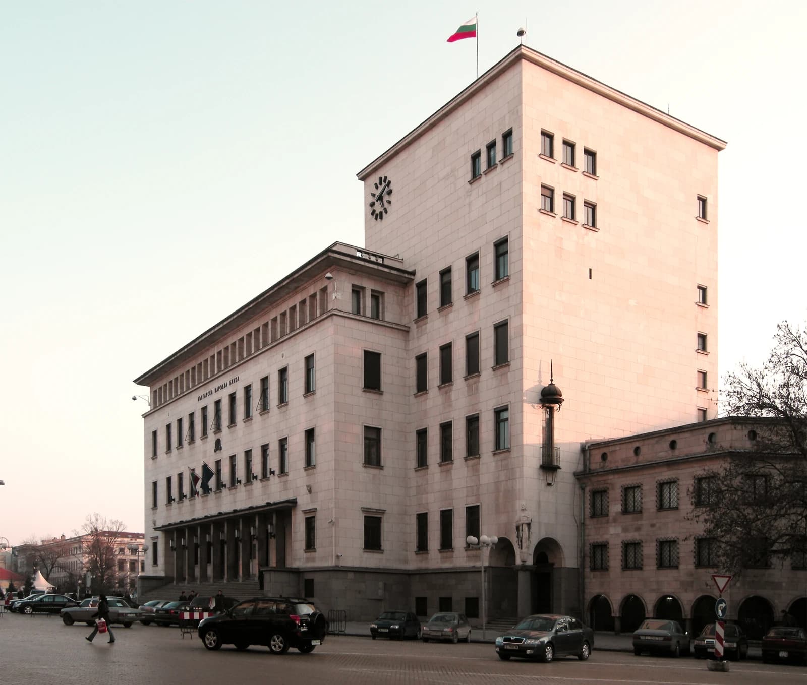 Exterior view of the National Bank of Bulgaria building in Sofia, with cars and people on the street.