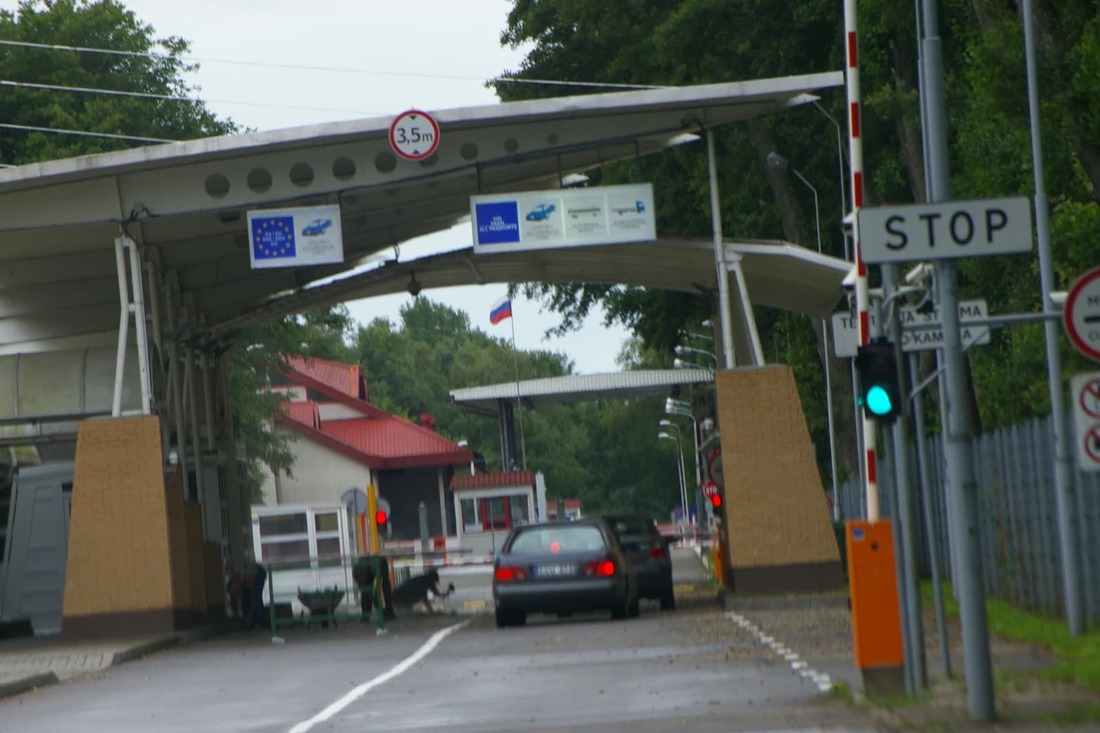 A vehicle border crossing point with a Russian flag and a "STOP" sign.