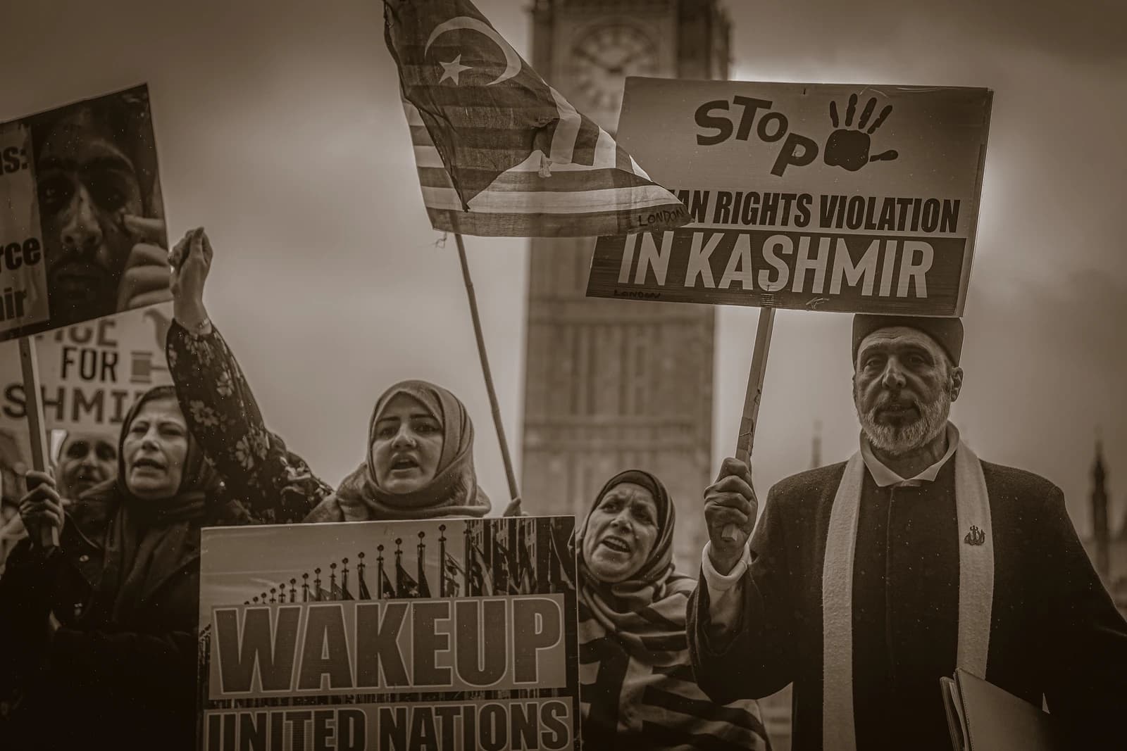 Activists holding signs and a flag during a protest in central London.