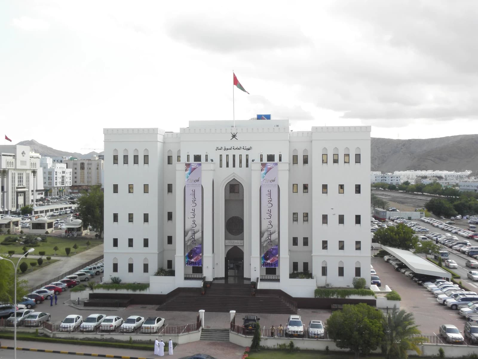 Exterior view of the Muscat Securities Market building in Oman with cars parked nearby.