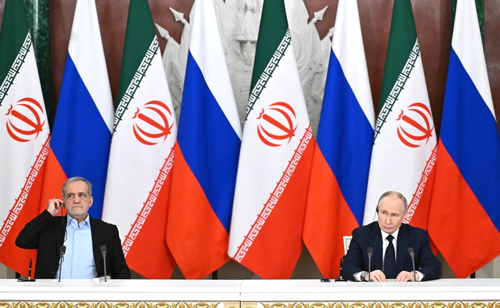 Vladimir Putin, President of Russia, sits at a table with an Iranian official.