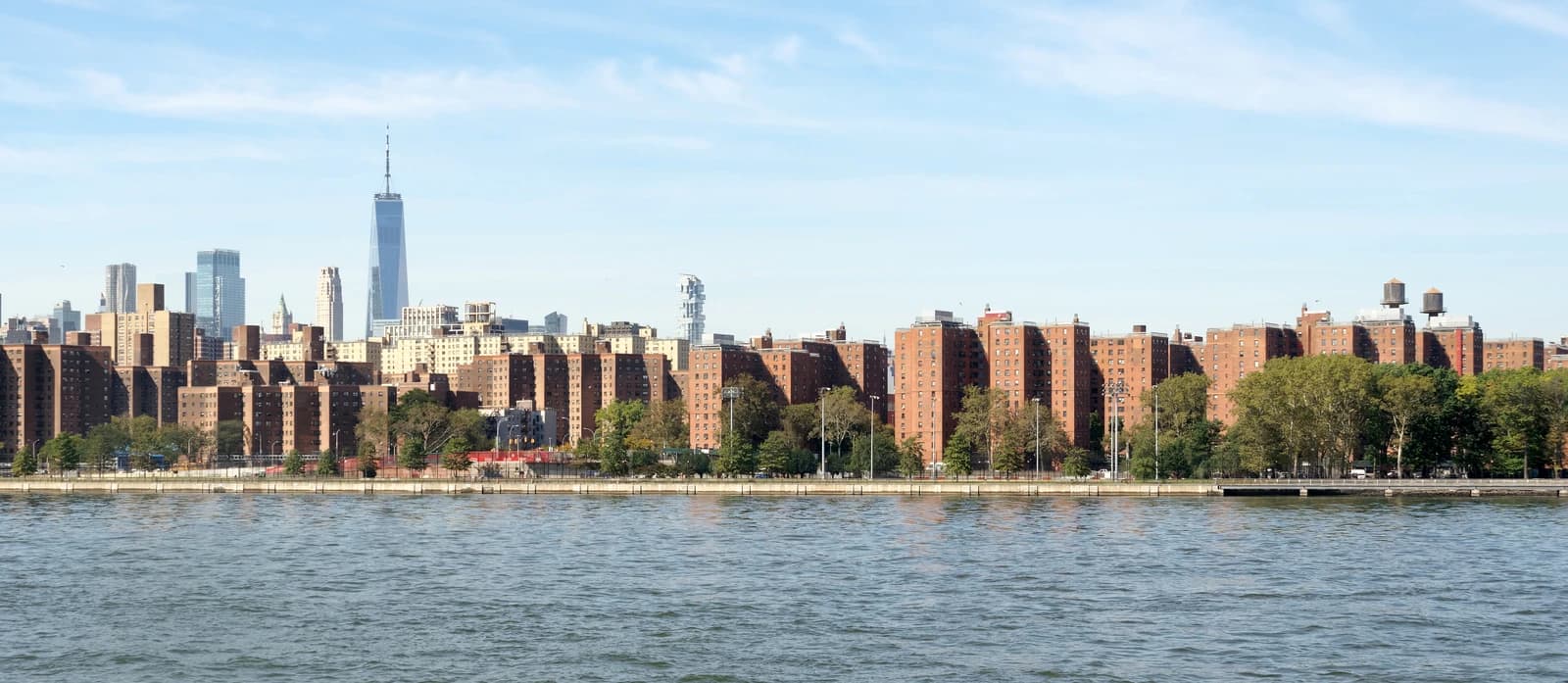 Apartment buildings on the bank of East River, New York City, with skyline in background.