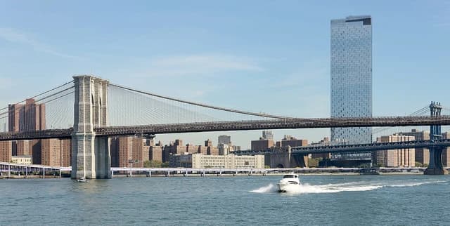 Brooklyn Bridge and Manhattan Bridge crossing a river, with city buildings in the background.
