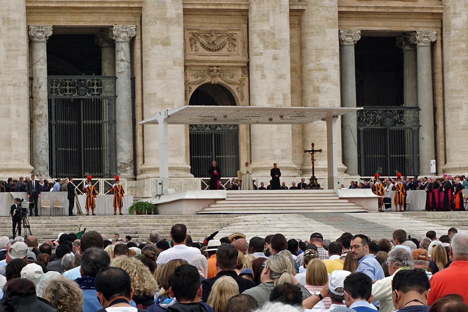 Pope Francis on a stage with a crucifix, addressing an audience in Vatican City.