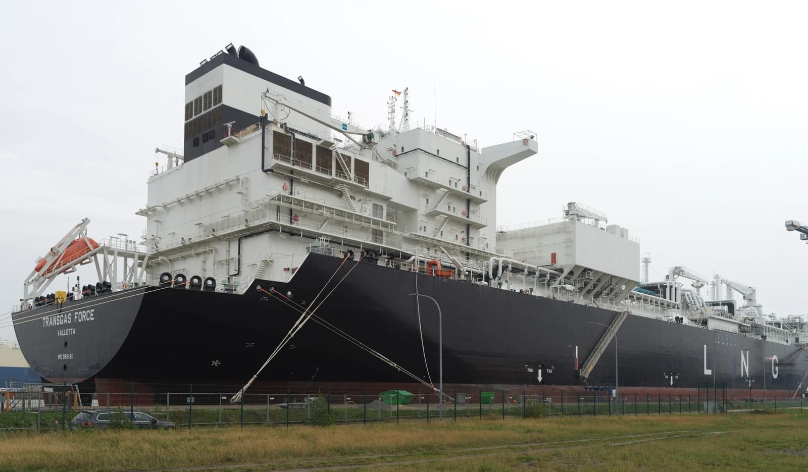 Floating Storage Regasification Unit, Transgas Force, moored at an industrial dock.