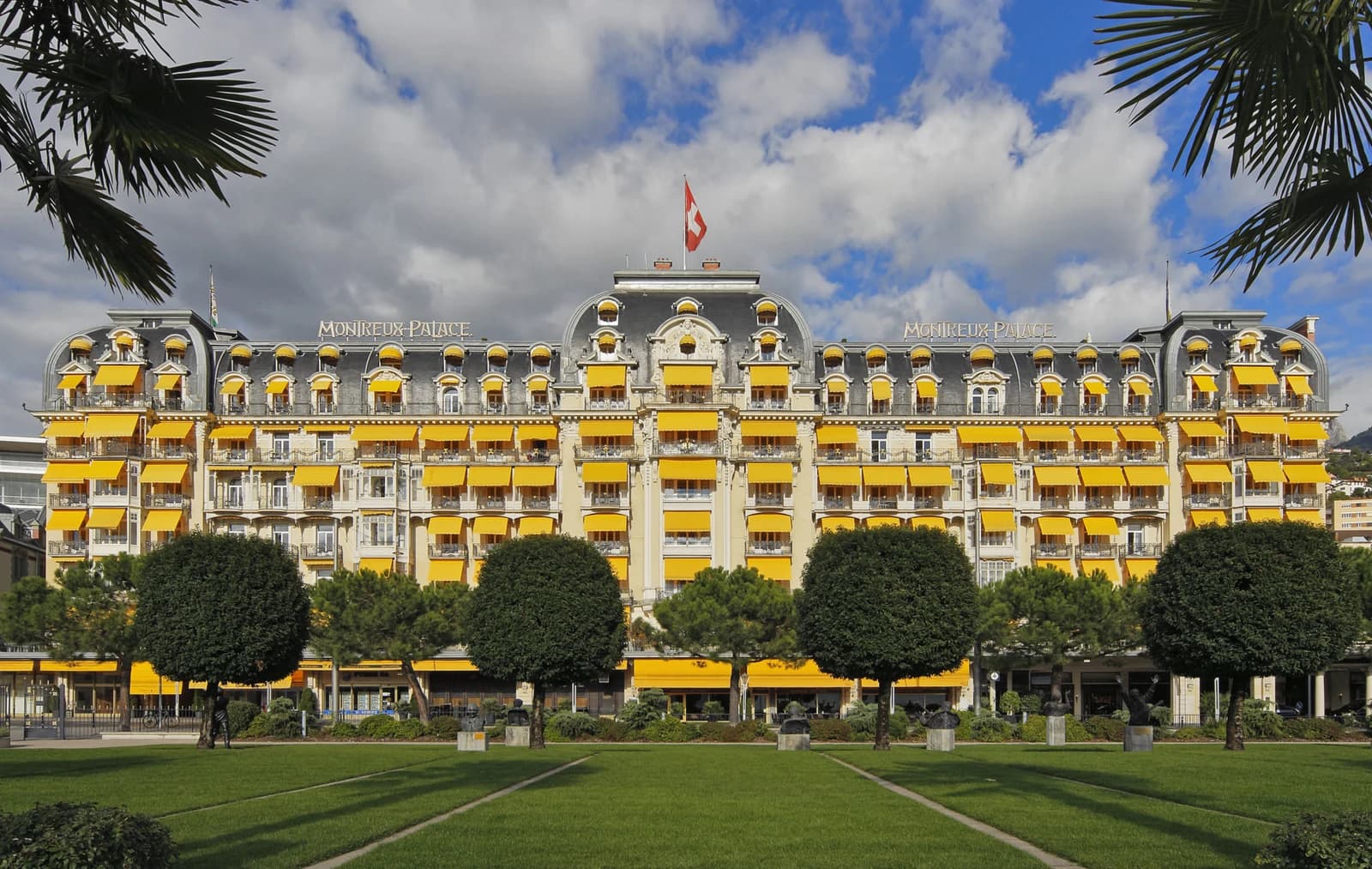 Fairmont Le Montreux Palace hotel with yellow awnings and a Swiss flag.