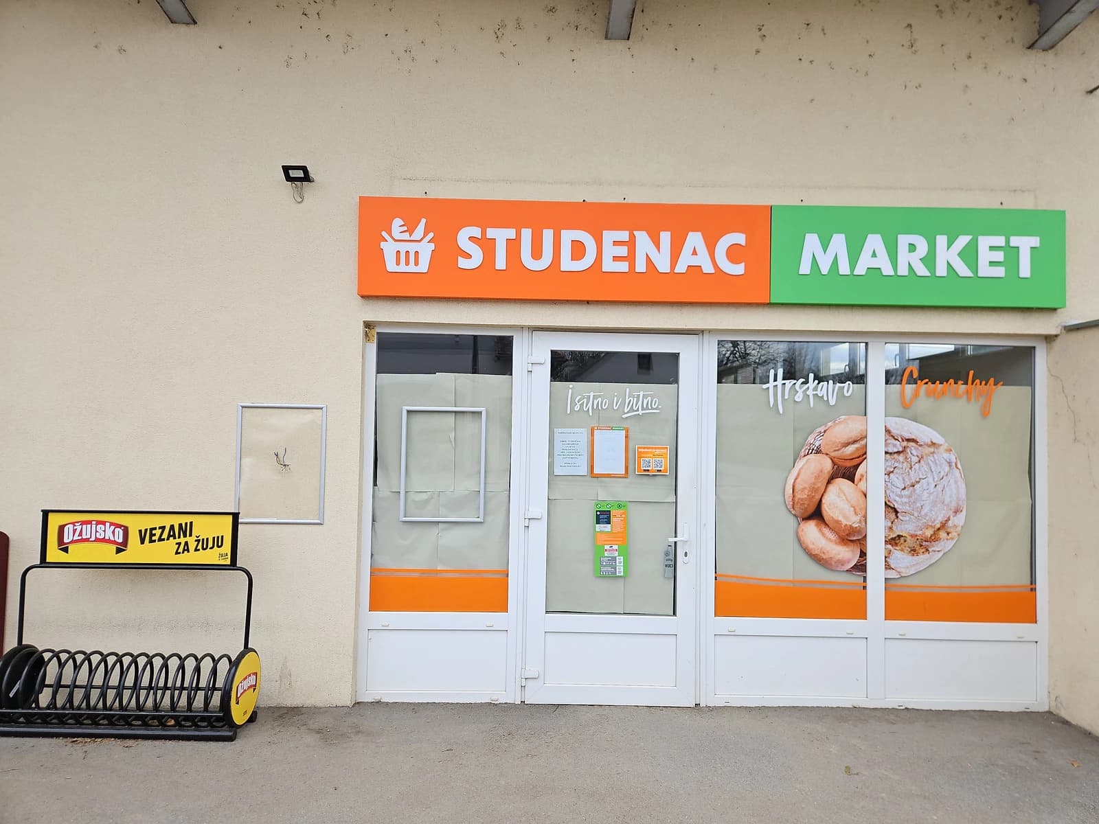 Storefront of a Studenac Market showing a bread display in the window.