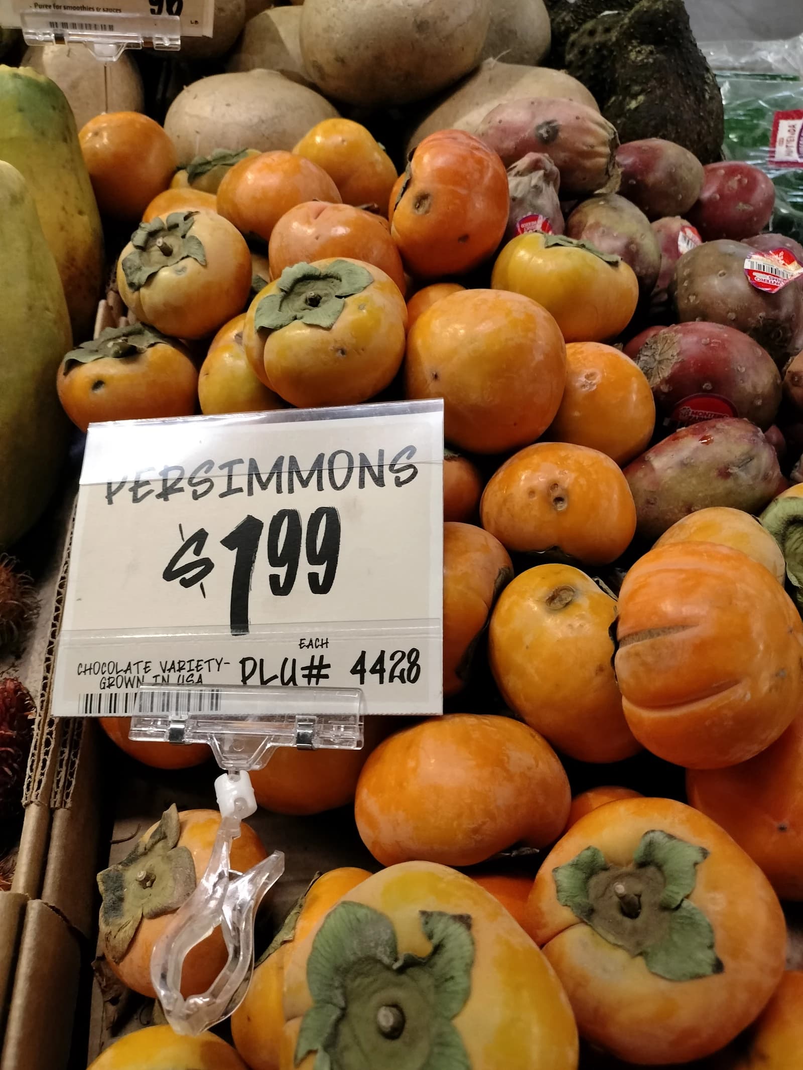 Orange persimmons with green tops displayed for sale in a grocery store.