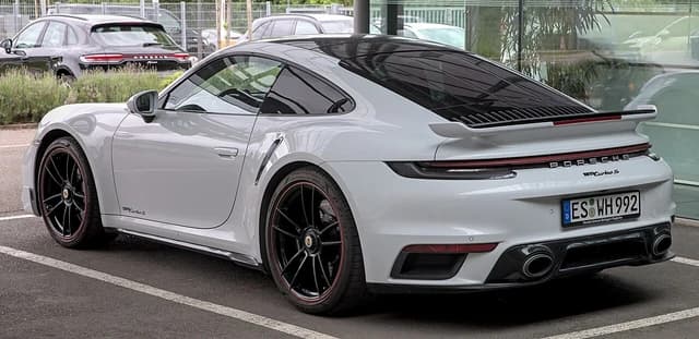 White Porsche 992 Turbo S, seen from the rear three-quarter angle, parked.