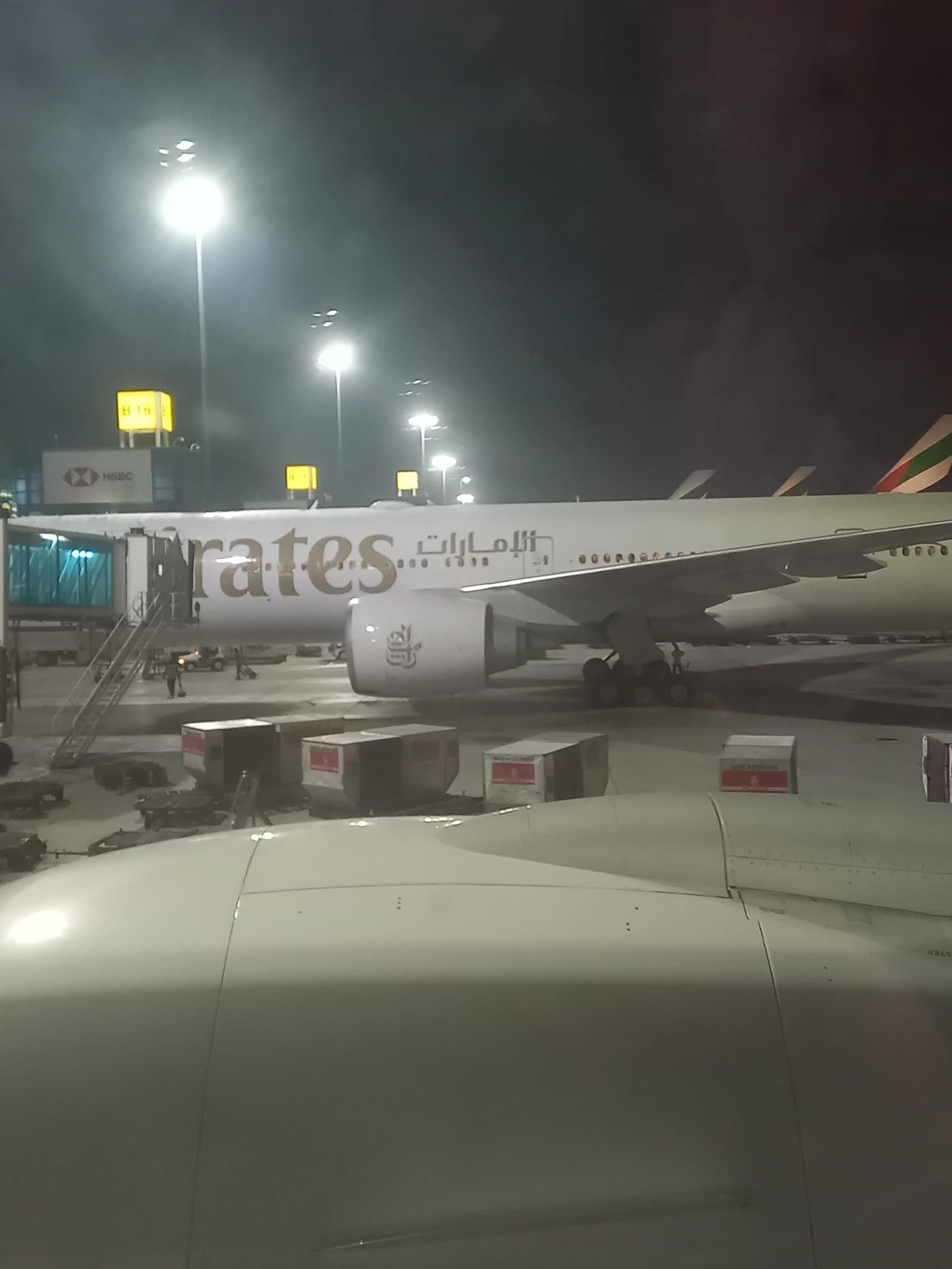 Emirates Airlines aircraft parked at a gate in Dubai at night.