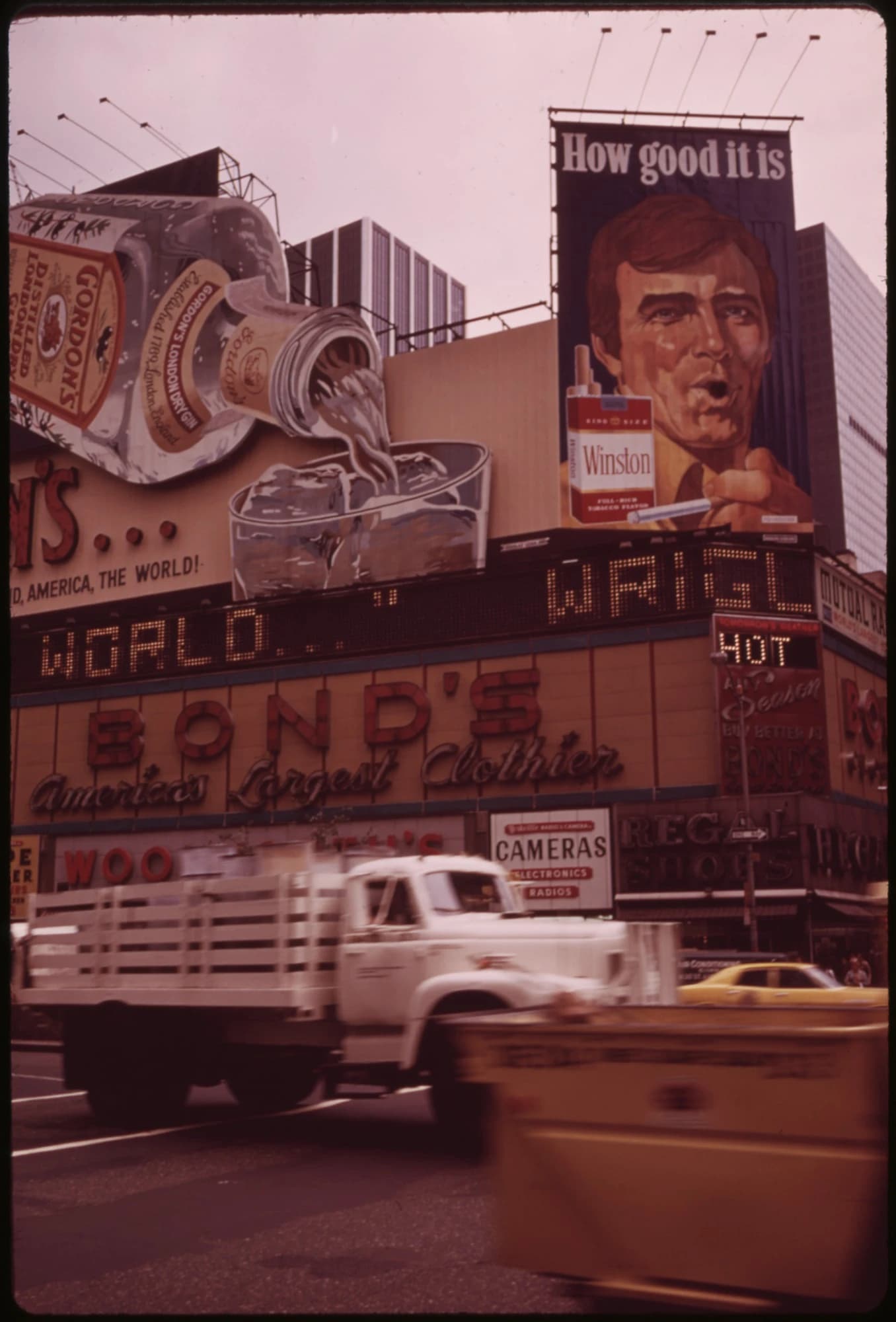 View of Times Square billboards including Gordon's Gin and Winston cigarettes, with blurred traffic.