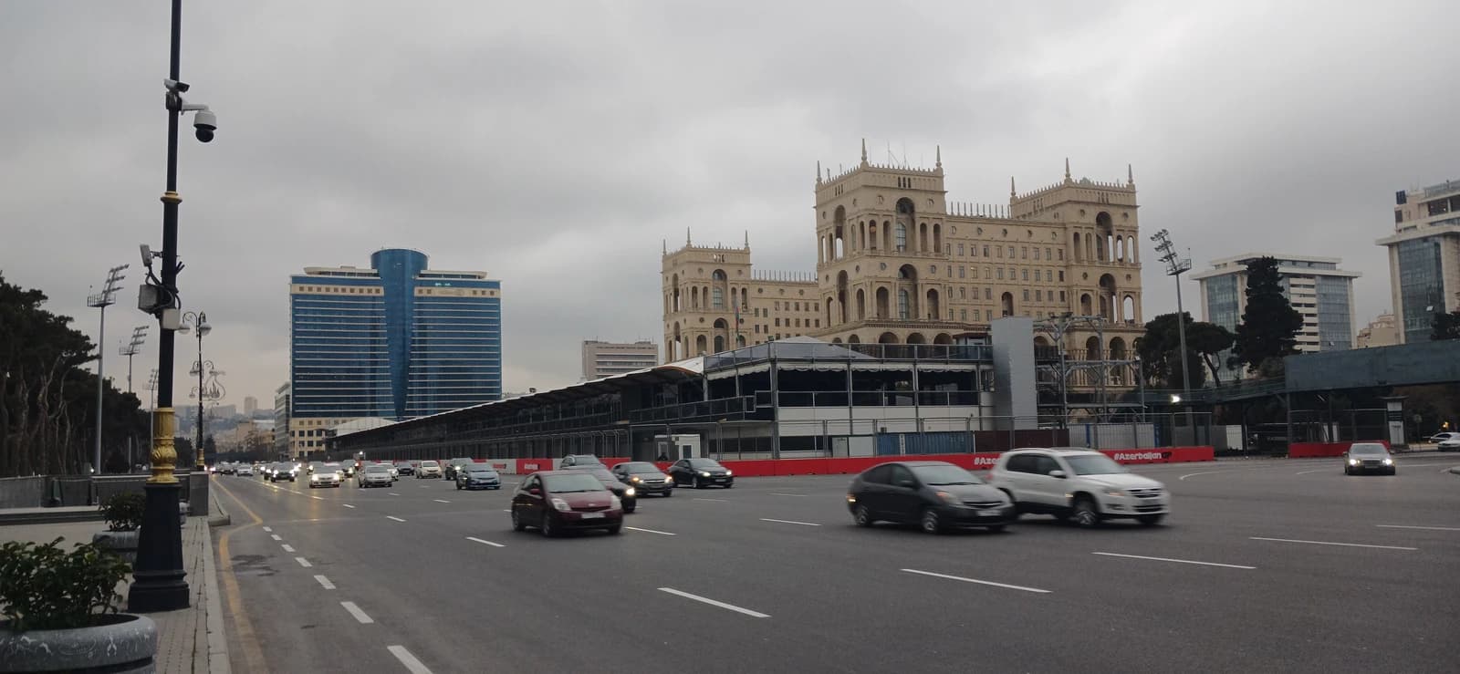 Traffic flows on a multi-lane road in Baku, with the Hilton Hotel and Government House visible.