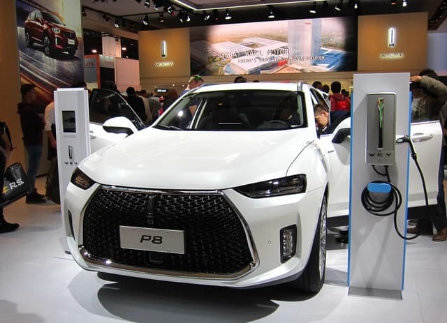 A white WEY P8 plug-in hybrid electric SUV on display at an auto show.