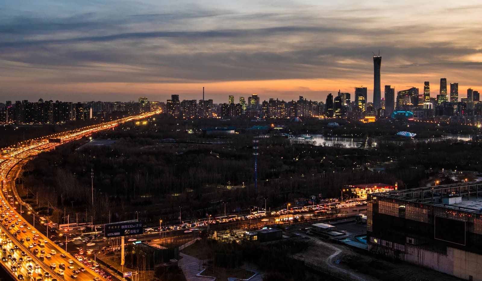 Aerial view of Beijing city skyline and illuminated roads at dusk.