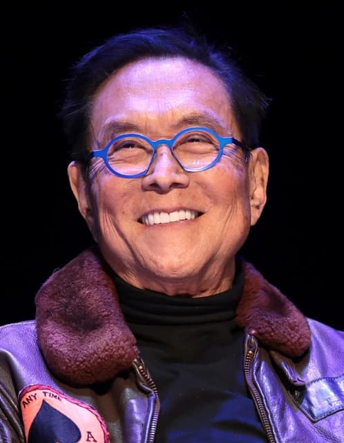 Robert Kiyosaki smiling and wearing blue glasses.