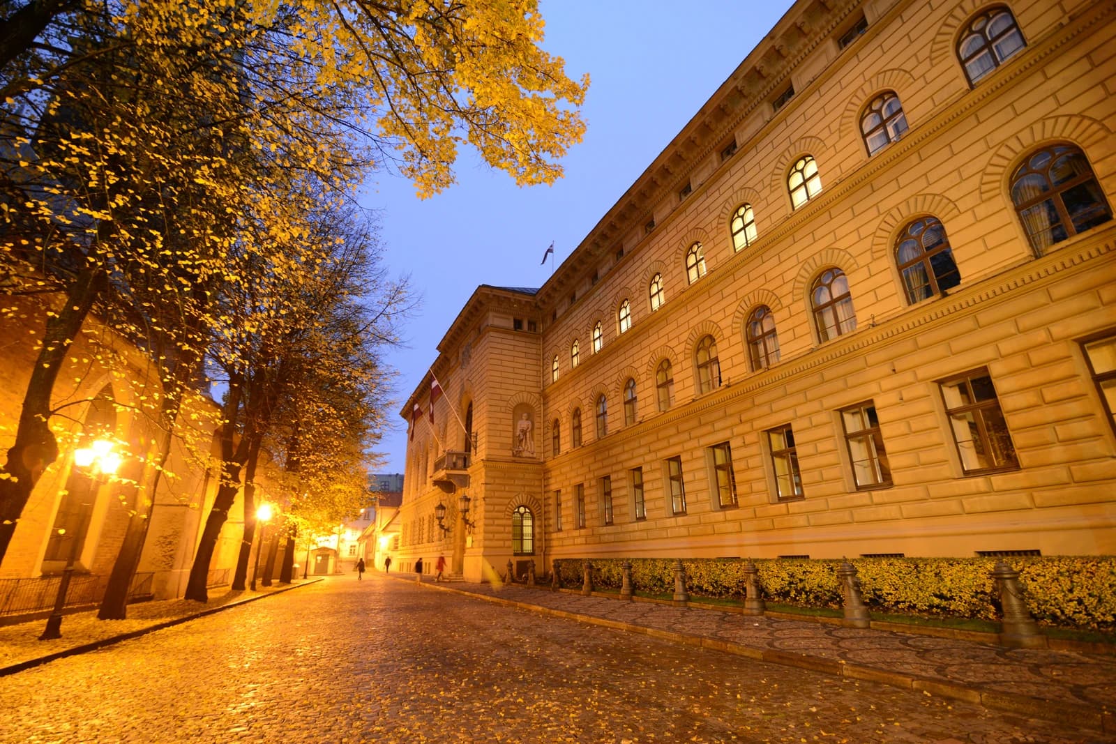 Exterior of the Parliament of the Republic of Latvia building at dusk, illuminated by streetlights.