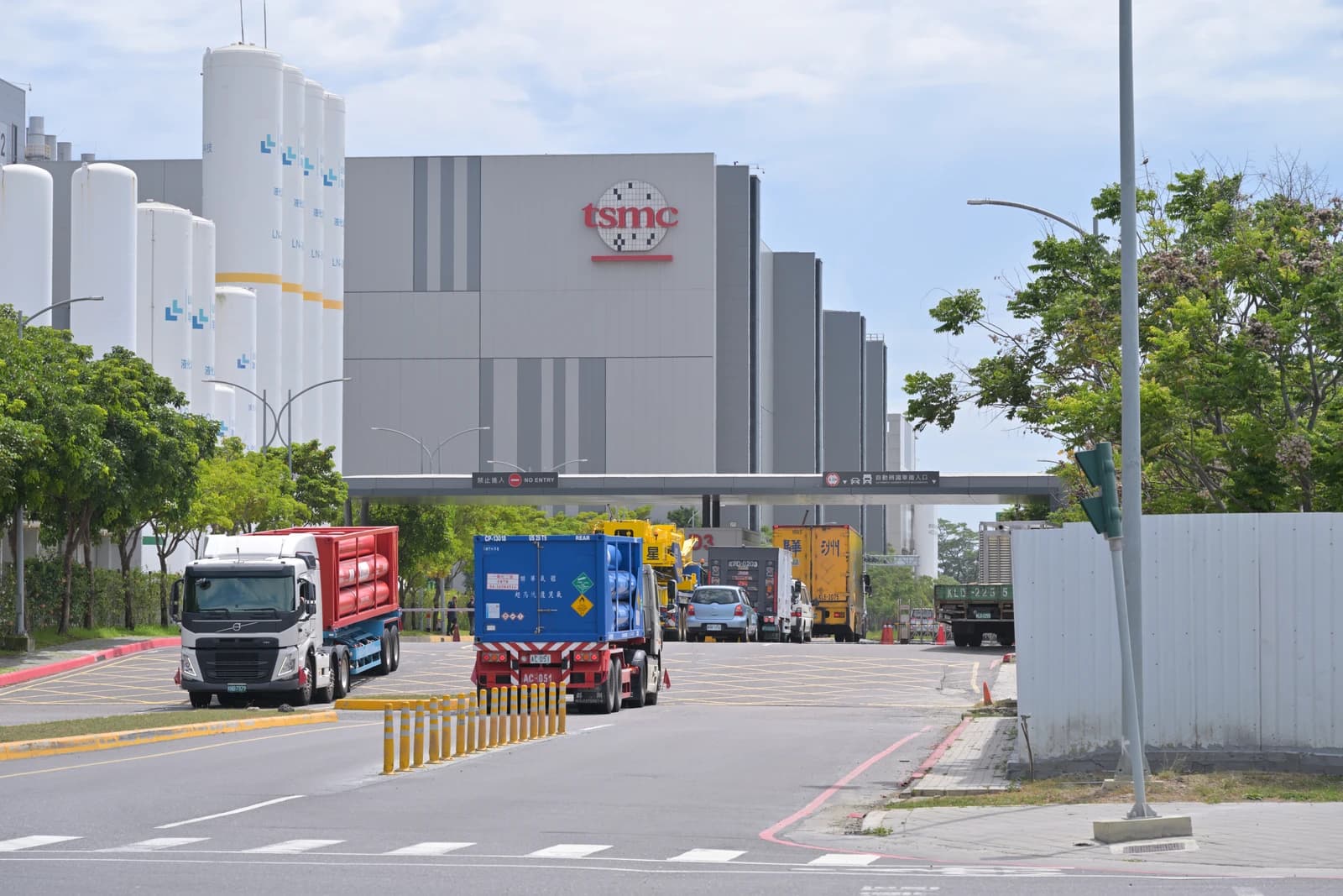 Trucks are entering and leaving TSMC Fab 18 facility on a sunny day.