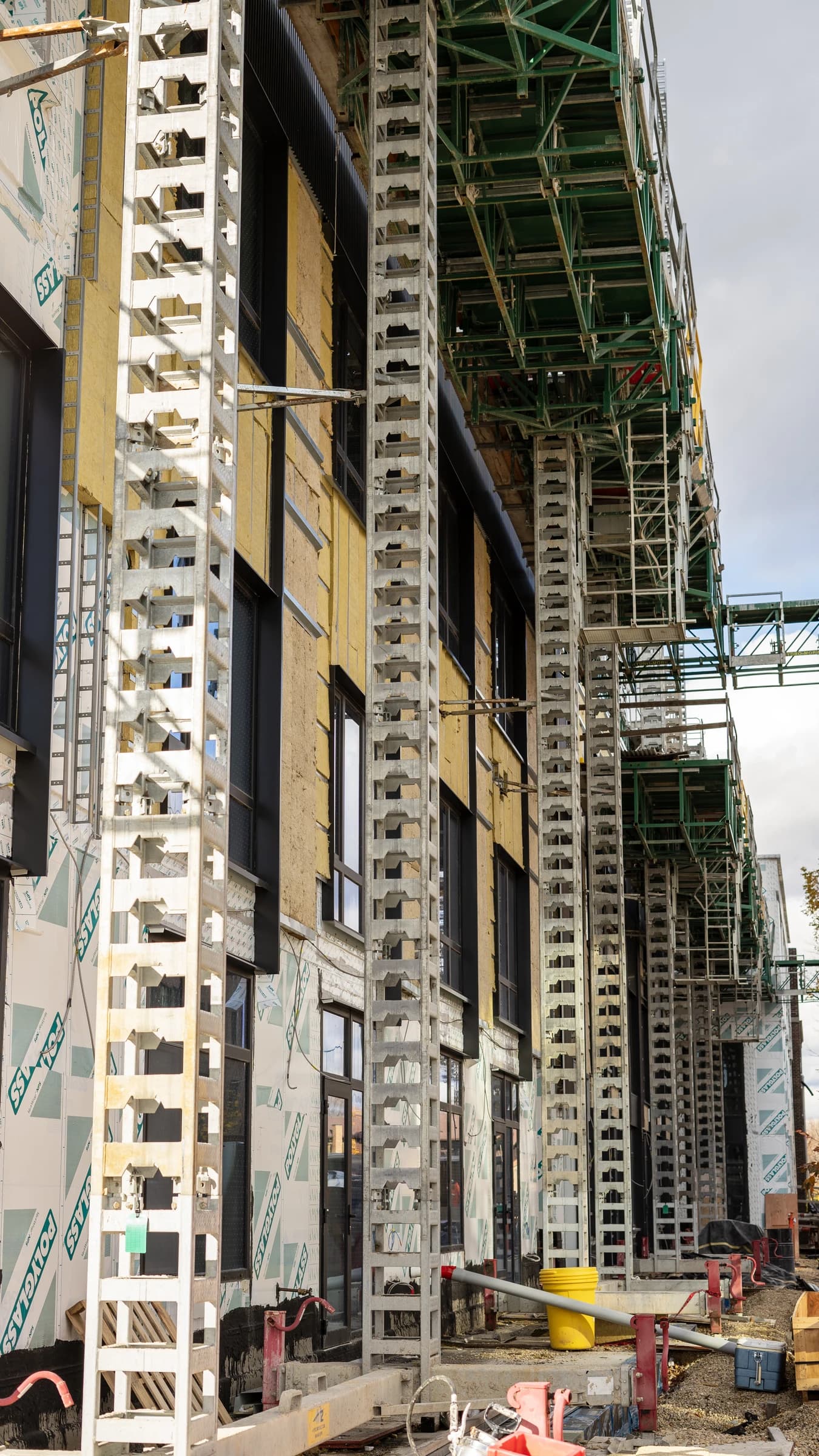 Exterior of Bakers Place modular building under construction with scaffolding and insulation materials.