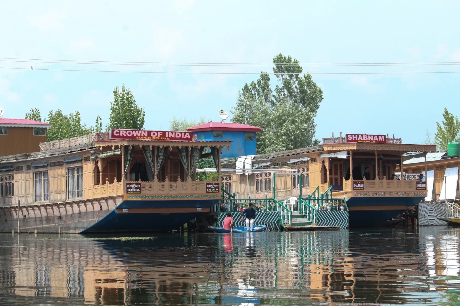 Houseboats with ornate wooden exteriors and reflections on a calm lake.