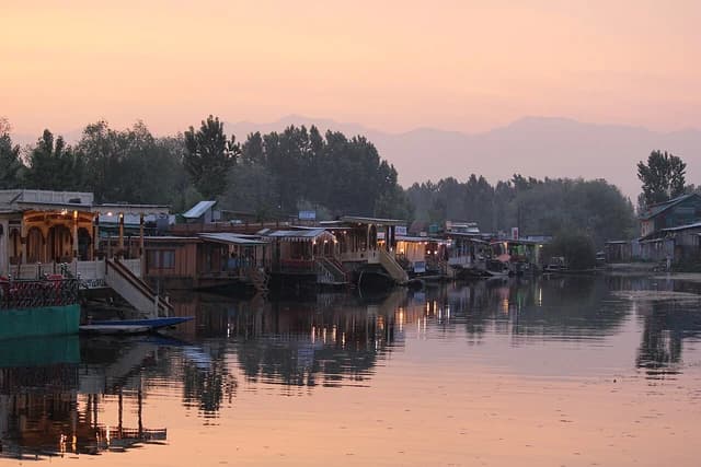 Houseboats are moored along the edge of Dal Lake in Srinagar during twilight.