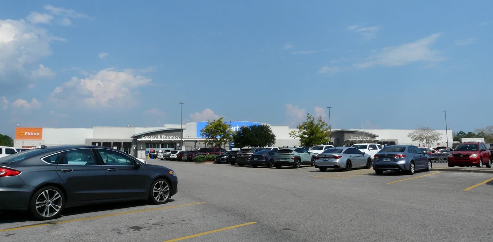 Walmart store exterior with 'Grocery & Pharmacy' entrance and 'Pickup' sign visible.