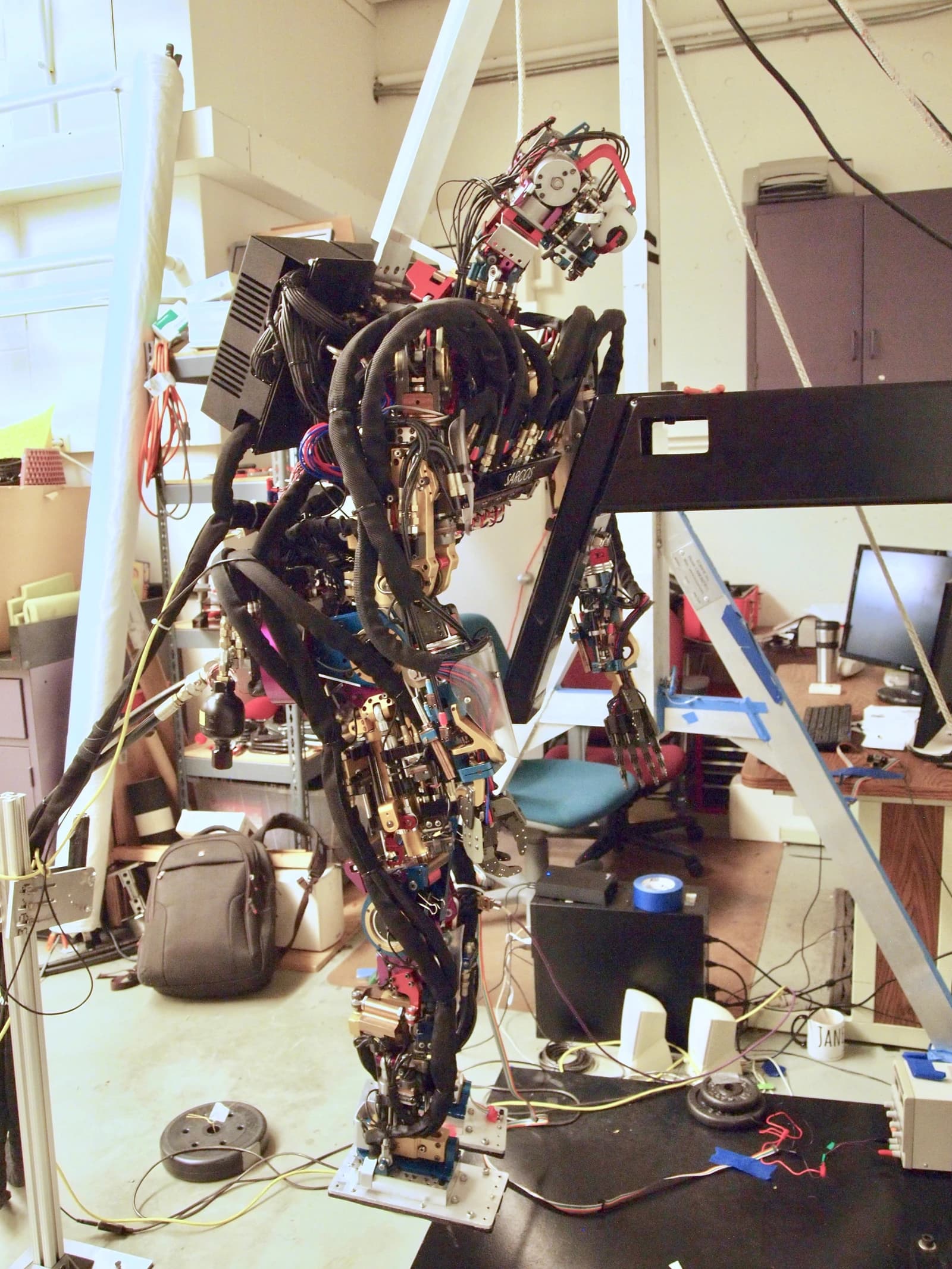 SARCOS humanoid robot prototype with visible wiring and components in a workshop.