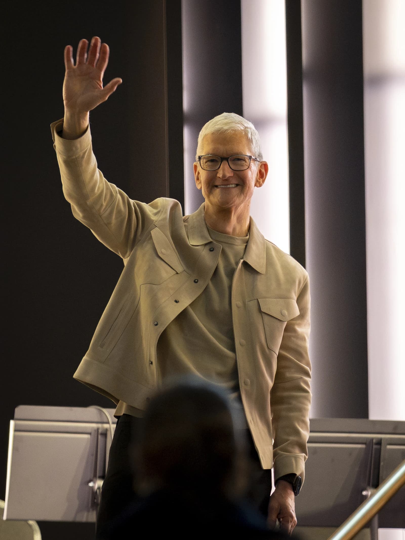Tim Cook, CEO of Apple, waving with his right hand.