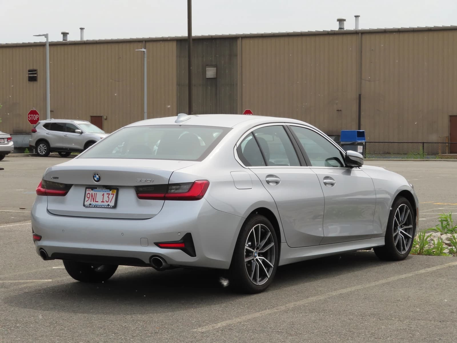 Silver BMW 3 Series sedan parked in an outdoor lot, seen from the rear three-quarter view.