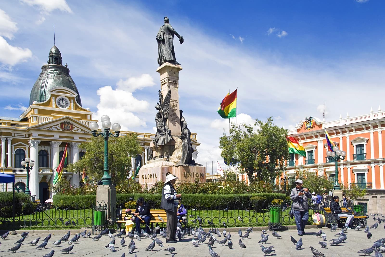 People and pigeons in Plaza Murillo, La Paz, Bolivia, with government buildings in background.