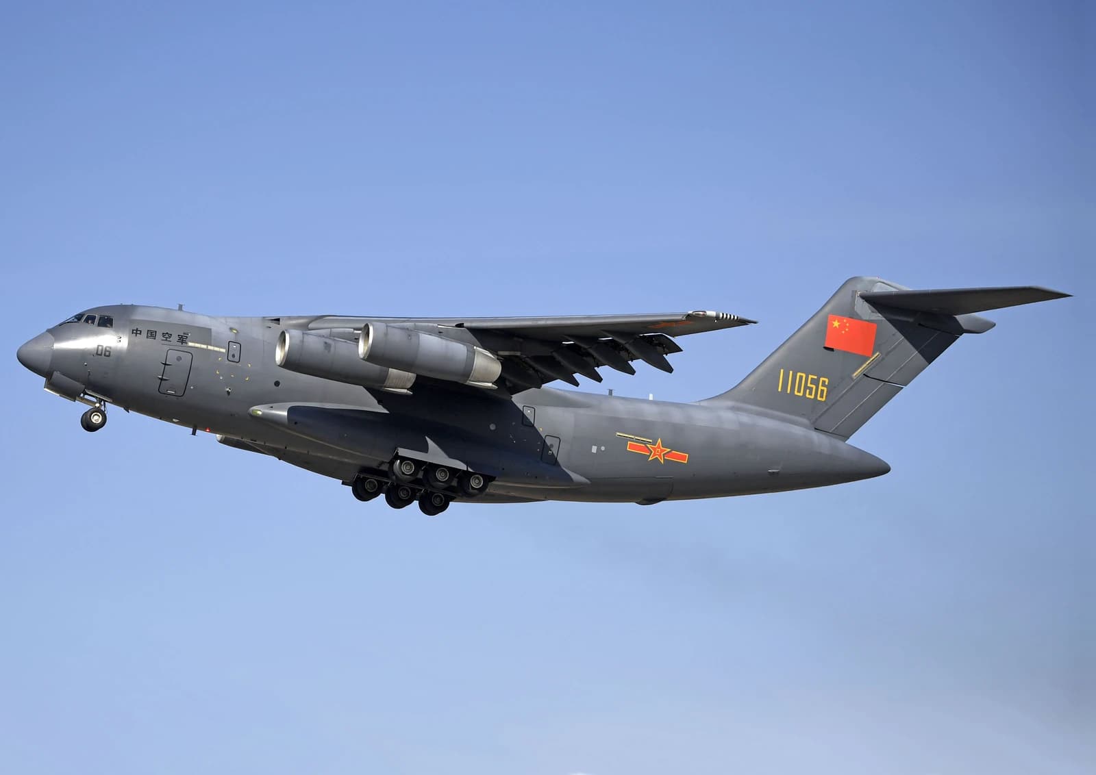 A gray People's Liberation Army Air Force Y-20 military transport aircraft flies against a blue sky.