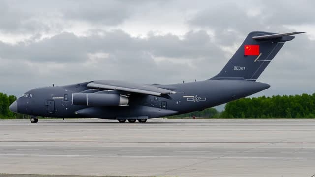 Chinese Air Force Xian Y-20 transport aircraft on a tarmac with a Chinese flag.