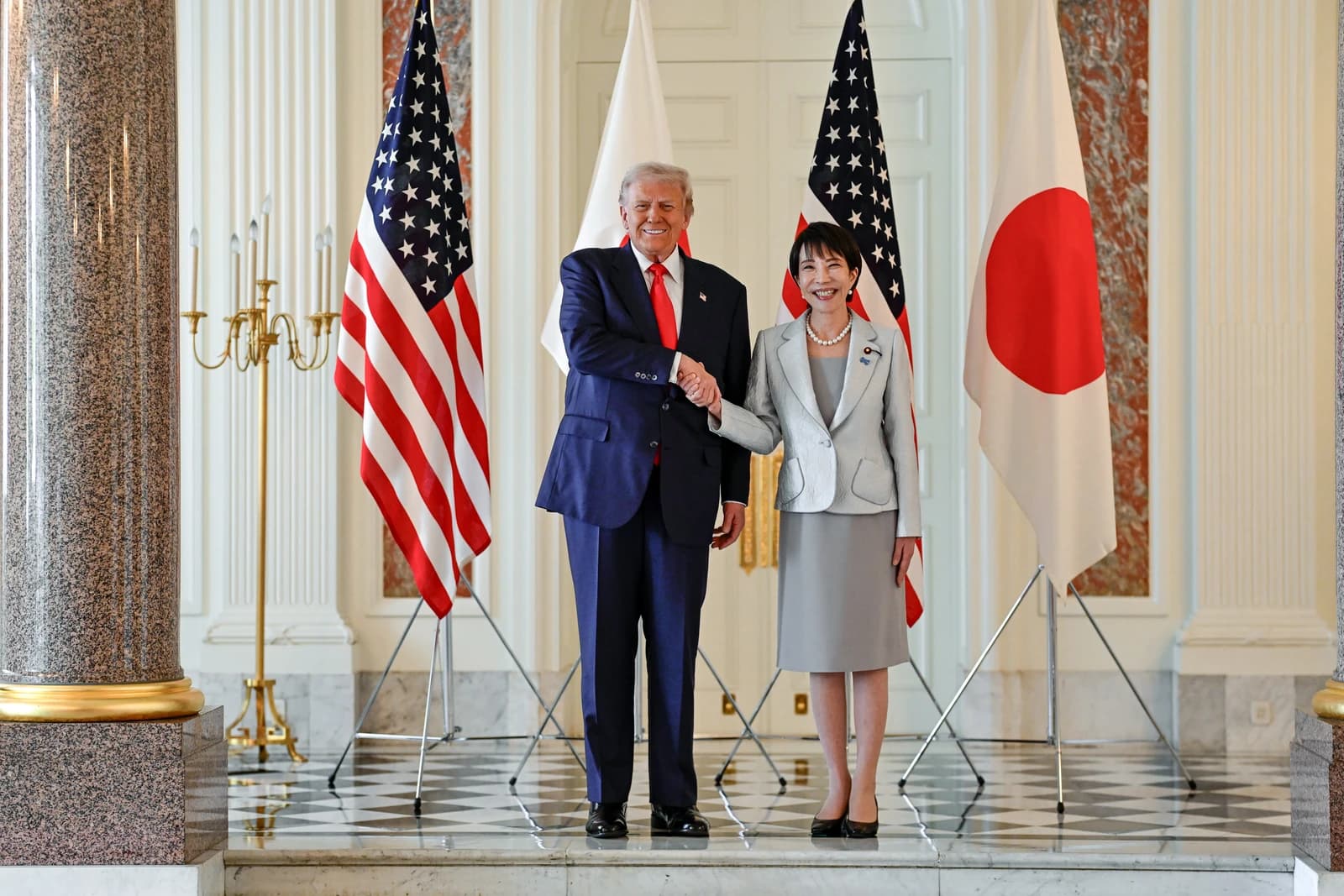 President Donald Trump and Japanese Prime Minister Sanae Takaichi shaking hands indoors.