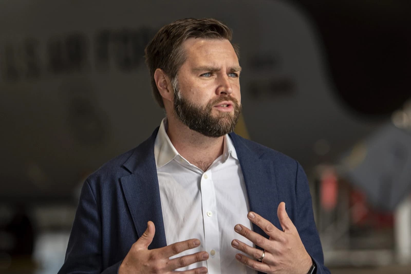 Senator J.D. Vance speaking and gesturing with both hands indoors.