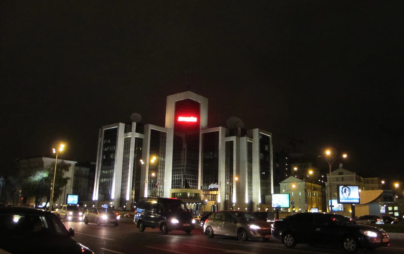 Lukoil Headquarters building illuminated at night with streetlights and cars.