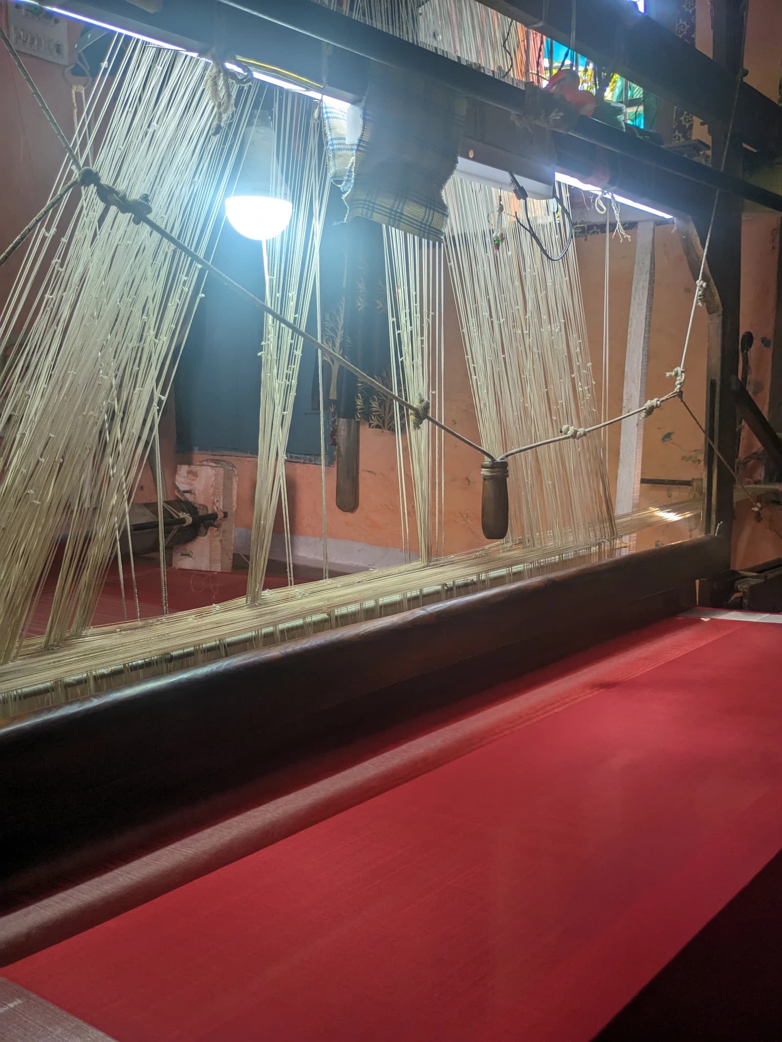 Close-up of threads on a traditional weaving loom in a craft village.