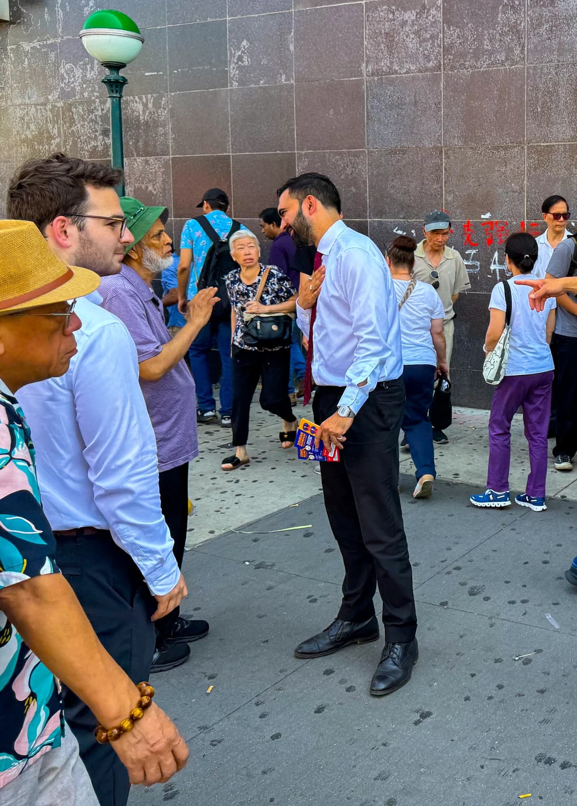 Zohran Mamdani, New York State Assemblyman, speaking with a constituent outdoors.