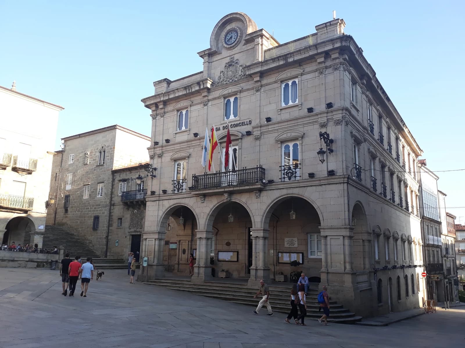 Ayuntamiento de Ourense, a grand stone building with arches and a clock, under a clear sky.