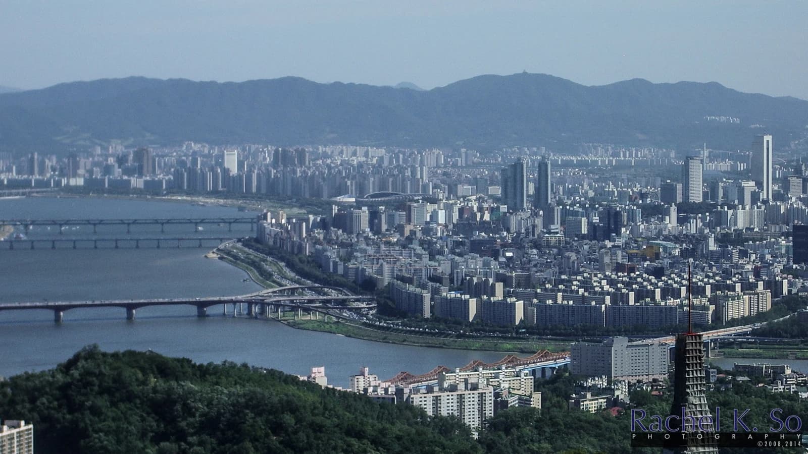East view of the Seoul cityscape with numerous buildings, bridges, and the Han River.
